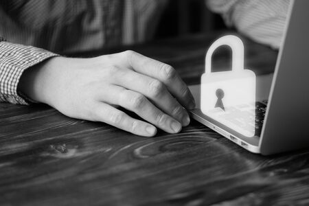 A man works at a laptop. Computer security concept. Close up.の写真素材