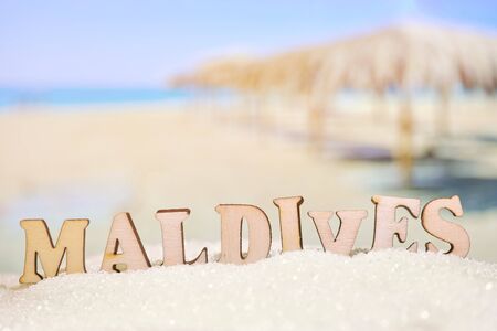 Abstract beach sand on a background of the sea with palm umbrellas with letters. Maldives is one of the most popular resorts in the world. Close up.の写真素材