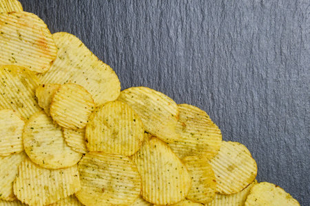 Corrugated chips on a black stone slate dish. Top view. Copy space. Close up.