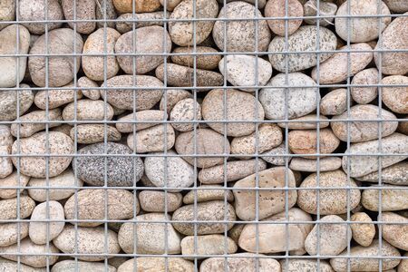 Wall with smooth stones in a grid. Background. Close up.の写真素材