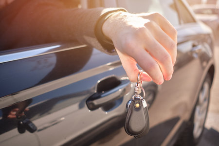 The man in the car put his hand out and holds the keys. Close up.