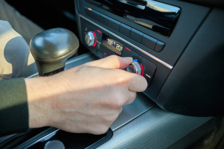 A man in a modern car. Hand switches the seat heating level. Close up.