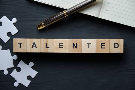Modern business buzzword - Talented. Top view on puzzle and notepad with wooden blocks. Close up. Top view.の写真素材