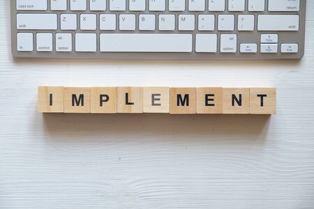 Modern business buzzword - implement. Top view on wooden table with blocks. Top view. Close up.の写真素材