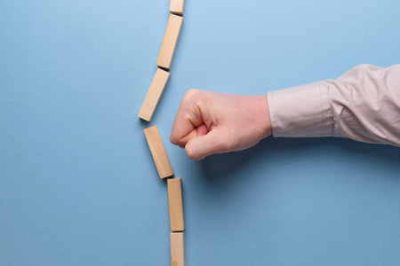 The concept of breaking stereotypes. Hand holds wooden blocks on a blue background. Close up.