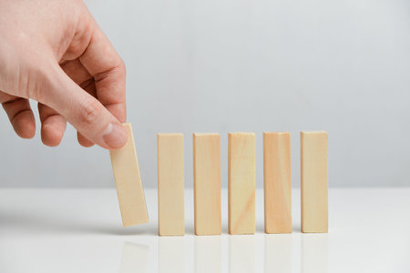 The concept of creating a phased business. Hand holds wooden blocks on a white background. Close up.