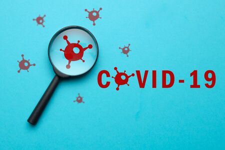 Coronovirus covid-19 answers and questions concept - magnifier with virus sign on blue background. Close up.の写真素材