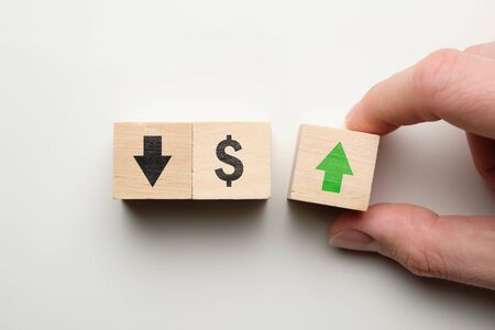 Dollar rising growth concept - hand holds cube with green arrow next to dollar sign. Close up.の写真素材