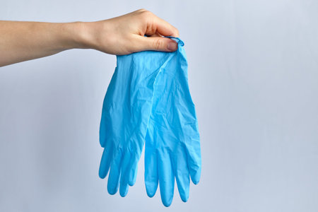 Hands hold blue medical gloves on a white background. Close up.