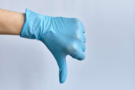 Dislike concept - hand in a medical glove on a white background. Close up. Copy space.