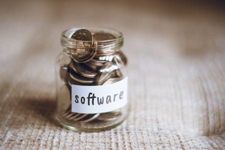 Savings concept for software - Glass jar with coins and inscription. Close up.