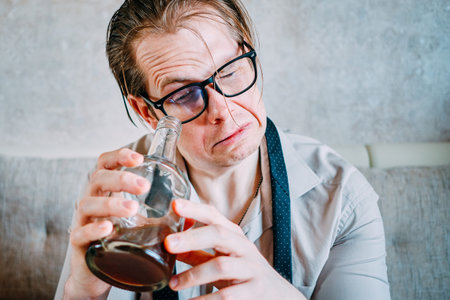 A drunk man drinks alcohol from a bottle. Close up.の写真素材