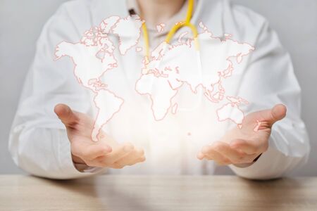A doctor with a stethoscope and abstractly holds a global healthcare concept. Close up.の写真素材