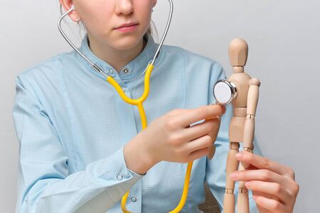 Doctor abstractly listens to the heart of a mannequin through a stethoscope. Close up.の写真素材