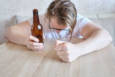 The drunken angry man swears to himself and knocks with his fist at home. Close up.の写真素材