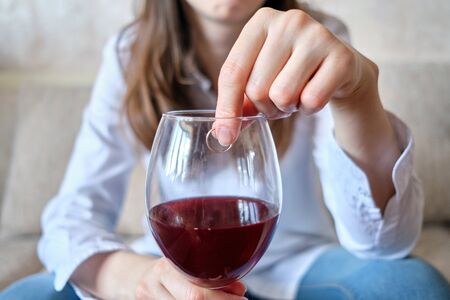 A drunk girl drinks wine and throws an engagement ring into a glass. Close up.の写真素材