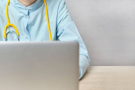 Girl doctor sits working at a laptop. Close up.の写真素材