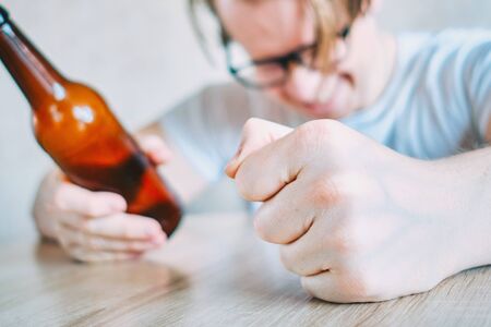 Glasses angry man drinks beer at the table. Close up.の写真素材