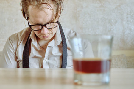 Drunk man in a shirt and tie drinks after being fired from work. Close up.