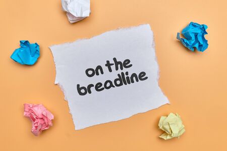 on the breadline - english money idiom hand lettering on wooden blocksの写真素材