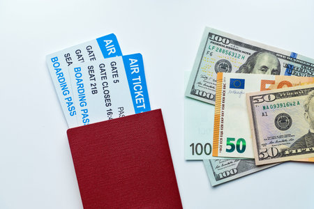 Passport with airline tickets and money with us dollars and euros on a white background with top view.の写真素材