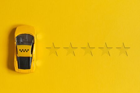 Taxi rating concept of 5 stars and cars with a sign on a yellow background with top viewの写真素材