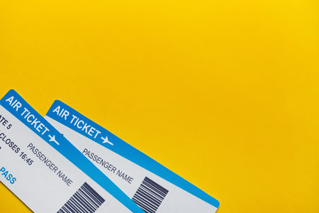 Airplane tickets on yellow background copy space and top view