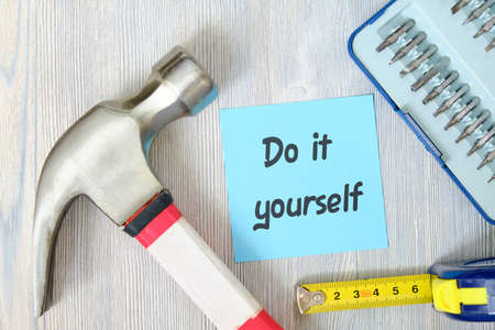 Tools repairman with the sticker and the inscription on it DIY on a white wooden background.の写真素材