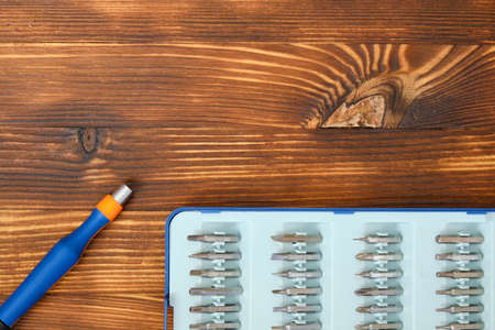 A screwdriver next to a case for interchangeable nozzles on a wooden background with a top view and copy spaceの写真素材
