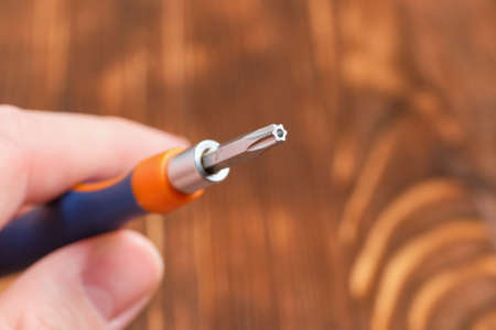 Screwdriver with interchangeable cross head in hands on a wooden backgroundの写真素材