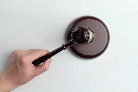 Hand knocking the table with a judge hammer.