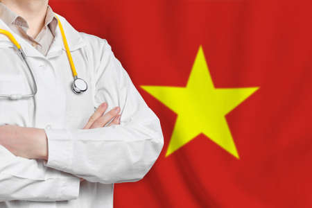 Socialist Republic of Vietnam healthcare concept with doctor on flag background. Medical insurance, work or study in the countryの写真素材
