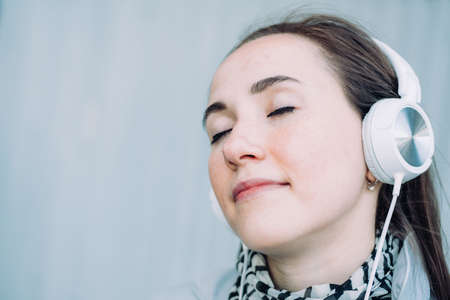 Caucasian girl in headphones smiles and listens to music with her eyes closedの写真素材
