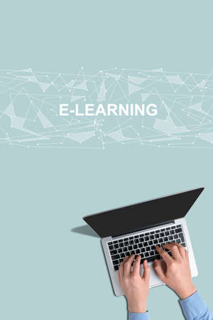 Hands with laptop with top view on a turquoise background with the inscription e-learning.の写真素材