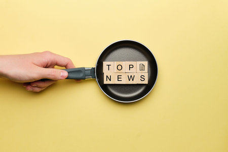 Top news concept on a frying pan on a yellow background