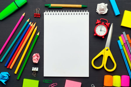 Back to school concept with stationery and notebook on wooden board.