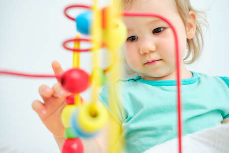 The toddler plays with her hands with learning toysの写真素材
