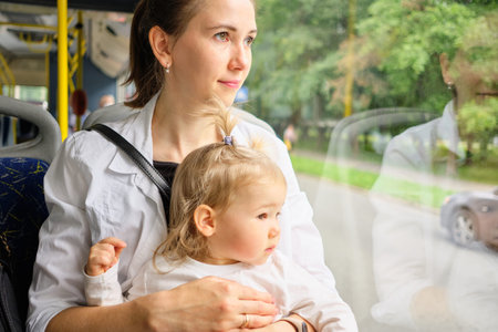 toddler and Mom sit on the bus seat and look out the window