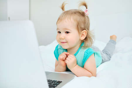 Happy smiling caucasian toddler girl playing on laptop.の写真素材