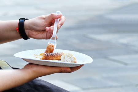 Person eating on the street grilled sausages.の写真素材