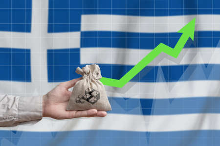 The concept of economic growth in Greece. Hand holds a bag with money and an upward arrow.の写真素材