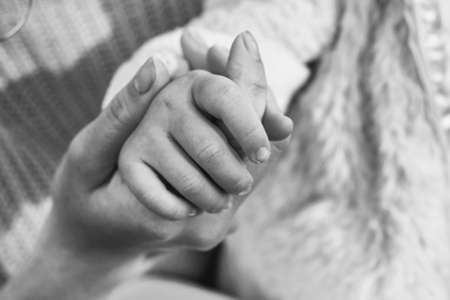 Mom holds the hand of her little baby close upの写真素材
