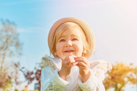 Child girl rejoices on a walk in the park on a sunny day.