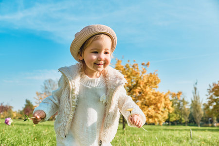 Caucasian child girl running in the park in autumn.