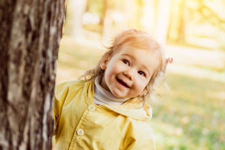 Joyful Caucasian child girl in next to a tree in autumn.の写真素材