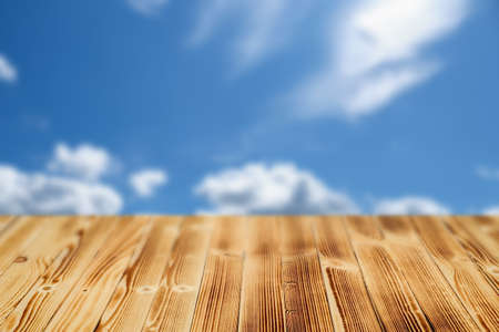 Wooden table with a blurry background of the sky with clouds.の写真素材