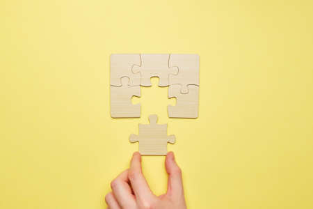 Person assembles a wooden puzzle and connects the last piece.の写真素材