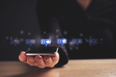 Social media concept with online activity. Abstract icons over a smartphone in the hands of a...