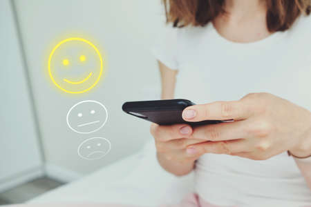 Good mood concept made of emoticon and rating. The girl uses the Internet through the phoneの写真素材