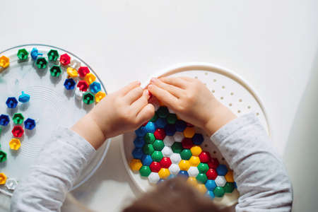 Child collects colorful mosaic in kindergarten top view.の写真素材